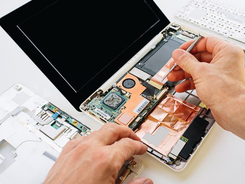 A computer repair specialist works on fixing a laptop.