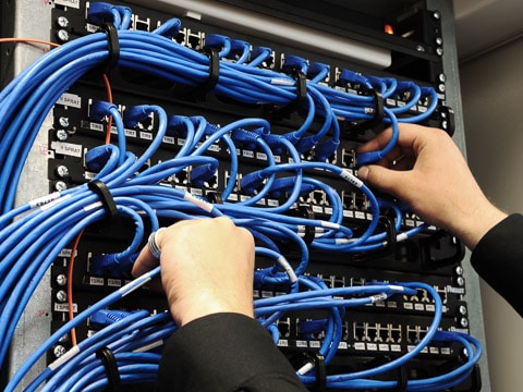 A specialist navigates the cables feeding a switch